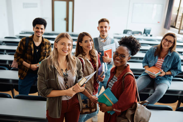group of young happy students in university classroom looking at camera.